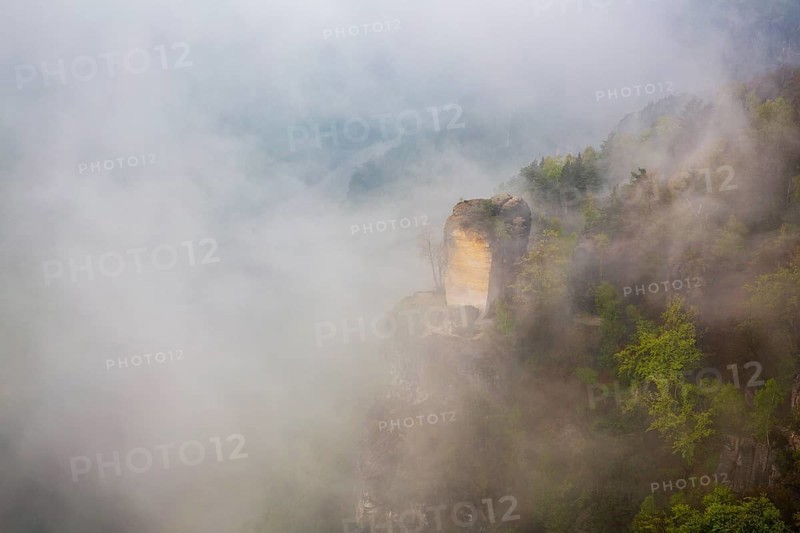 The bright Wartturm above the Elbe river, hidden in dense fog. Seen from the Bastei rocks near the village of Rathen in Saxon Switzerland National Park, Saxony, Germany. On November 22, 2000 the Wartturm was the scene of a spectacular rockfall