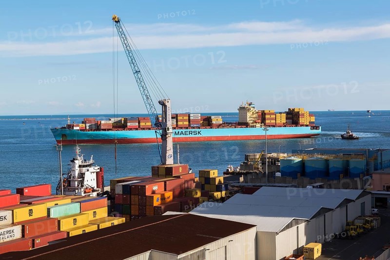 Maersk Serangoon cargo ship loaded with metal box shipping containers being guided by pilot boats into La Spezia cargo Port, Italy, Europe