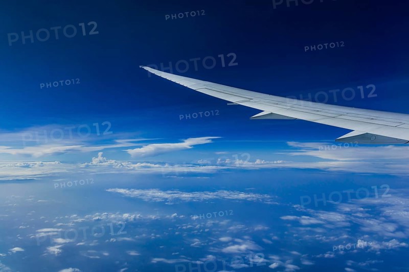 View from the aircraft window during a flight over India with the airline Etihad. Blue sky and cloud structures over the sea, wing of a Boeing 787 aircraft
