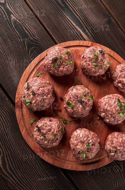 Raw meatballs, with micro greenery, on a cutting board, homemade, rustic, no people