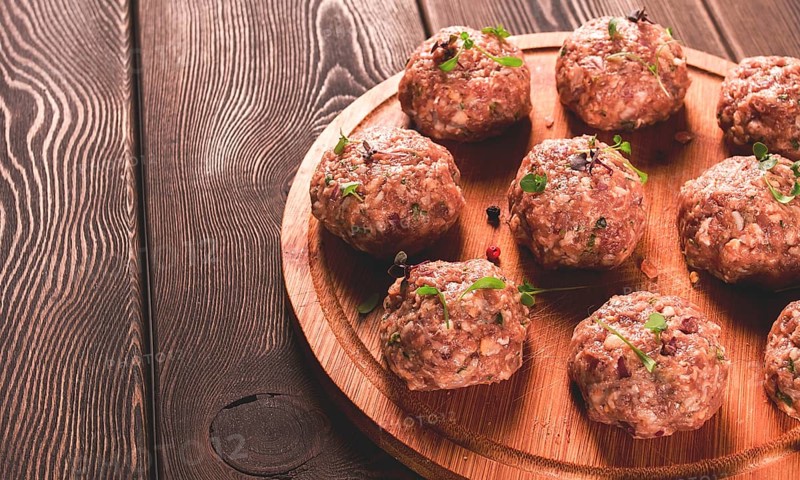 Raw meatballs, with micro greenery, on a cutting board, homemade, rustic, no people