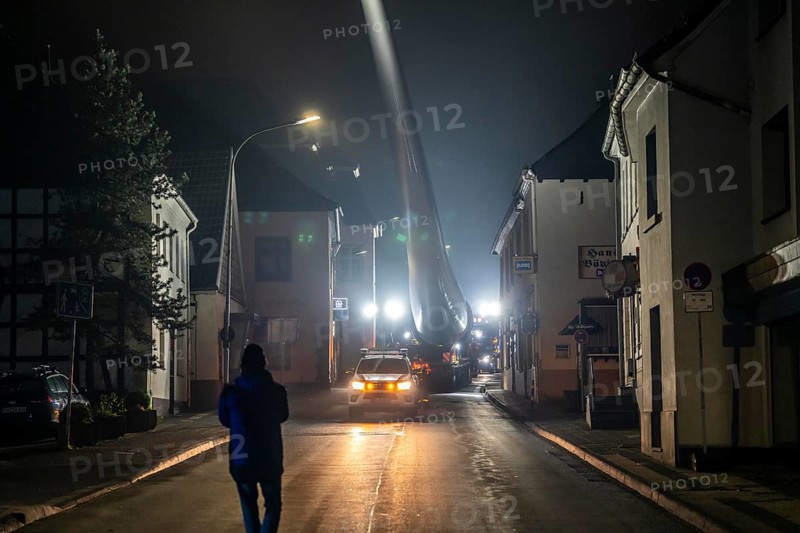 Transport of a 68 metre long, 22 tonne blade of a wind turbine, here in Breckerfeld, with a self-propelled Blade-Lifter vehicle, over a 40 km long route, over 2 nights, in the Bergisches Land, through towns, villages, over country roads, narrow through roads, to the construction site of the wind turbine near Hagen, North Rhine-Westphalia, Germany, Europe