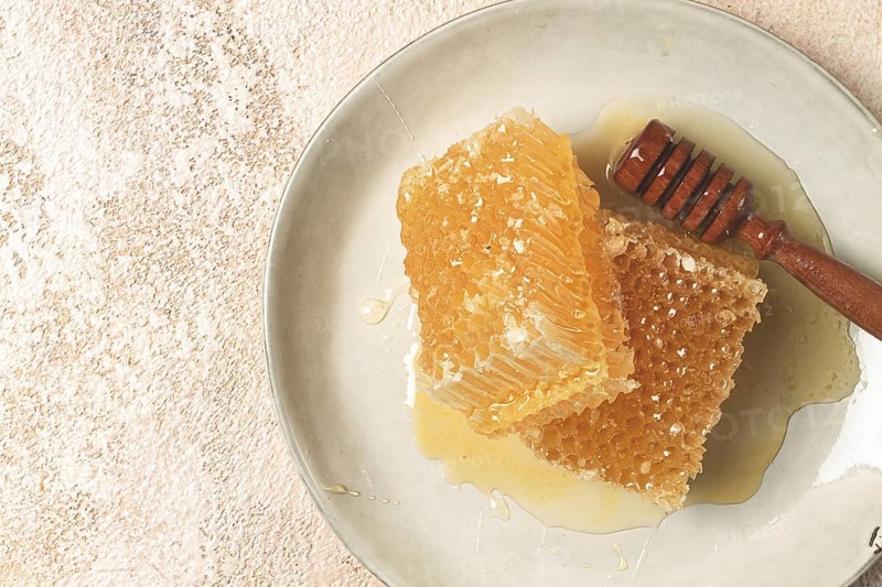 Honeycomb, with a wooden spoon-spindle, on a plate, no people
