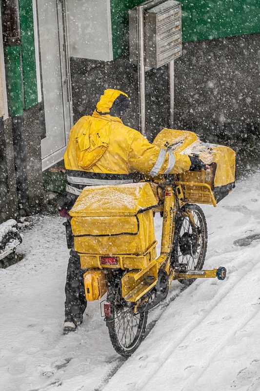 Winter weather, heavy snowfall, city centre traffic, postman with bicycle in the snow, Essen, North Rhine-Westphalia, Germany, Europe