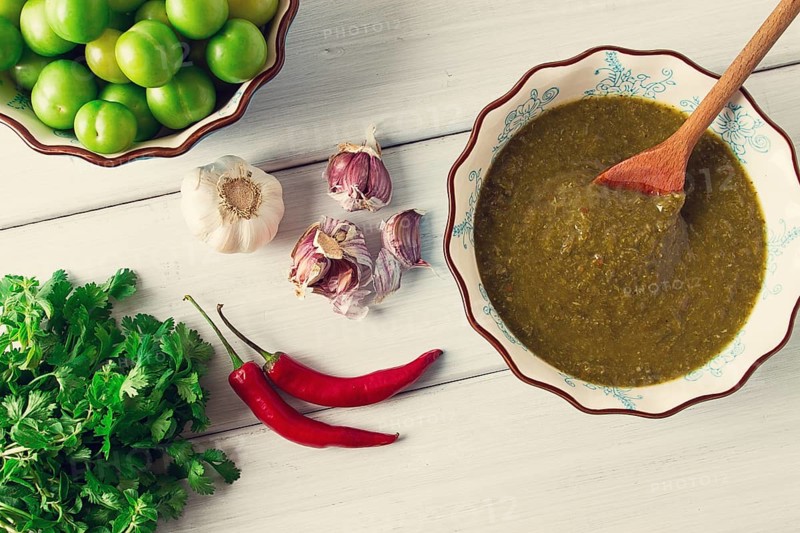Tkemali sauce, traditional Georgian cuisine, green cherry plum, with ingredients for sauce, cilantro, mint, hot pepper, garlic, on a white wooden table, close-up, rustic, food background, no people, selective focus, sauce, green sauce, tkemali, georgian cuisine, homemade
