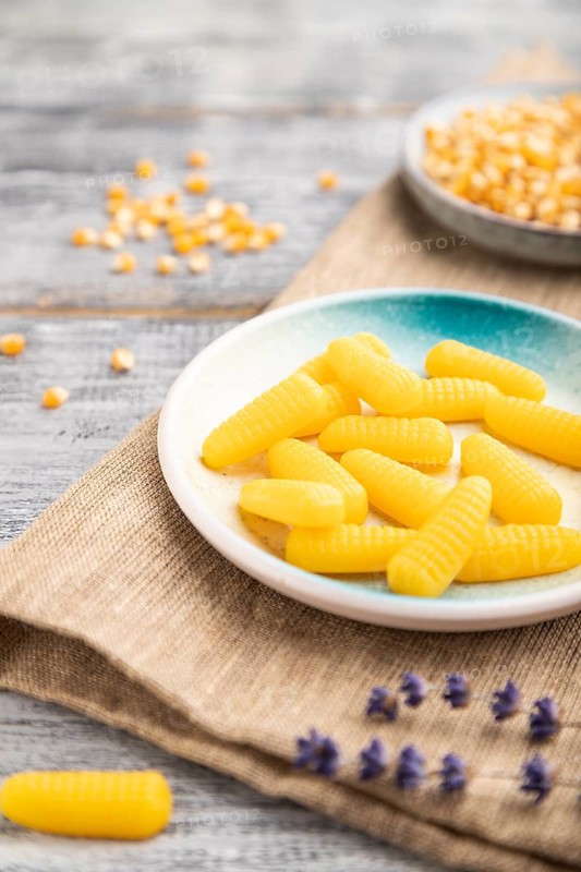 Jelly corn candies on gray wooden background and linen textile. close up, side view, selective focus