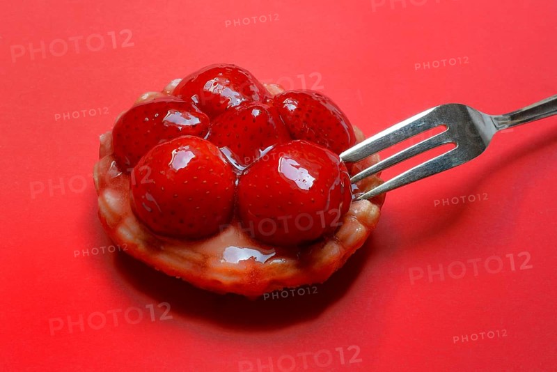 Strawberry tartlet with fork on red background, fruit cake
