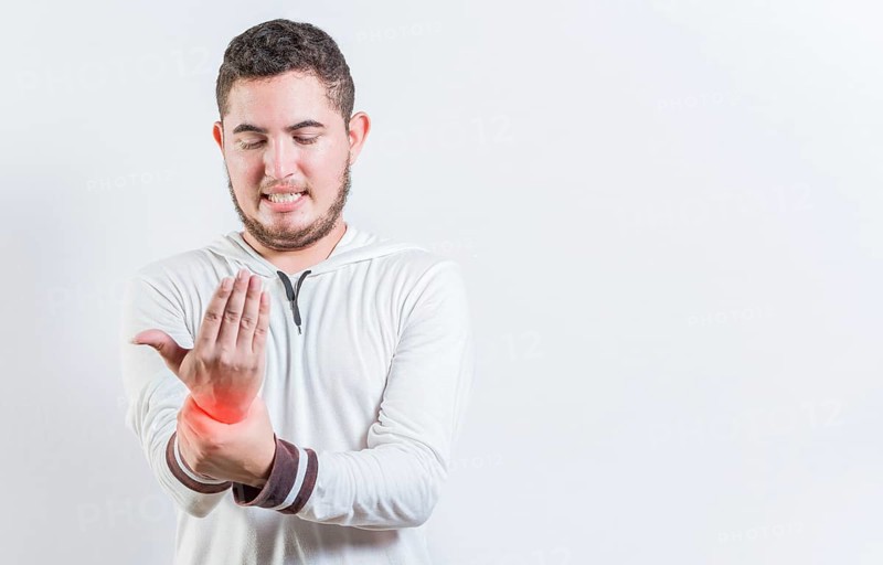 Person with arthritis pain rubbing hand isolated. Suffering young man with pain in hand joints isolated