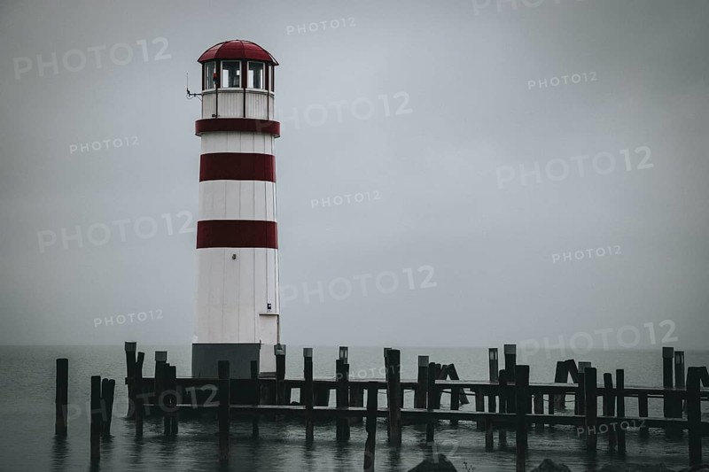 A red and white lighthouse stands on the lake on a foggy day, Podersdorf, Burgenland, Austria, Europe