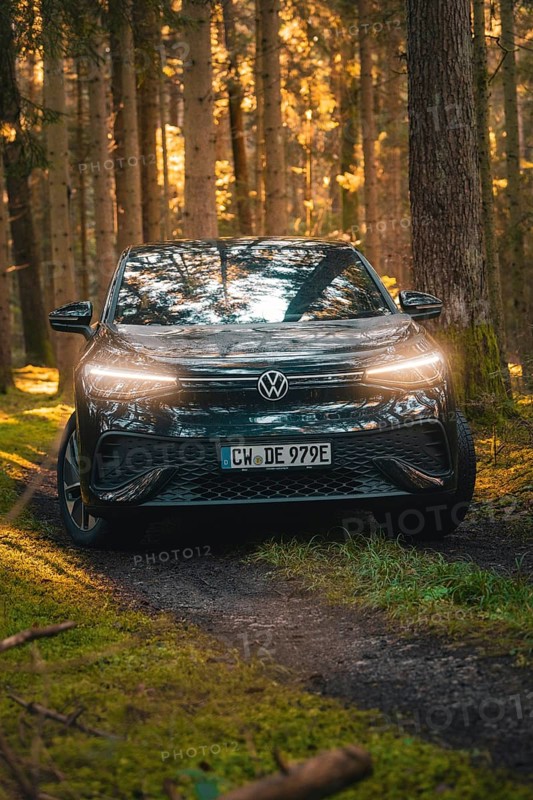 Black car standing on a forest path, bathed in warm light, car sharing vehicle Deer Mobility, electric car VW ID5, Black Forest, Germany, Europe