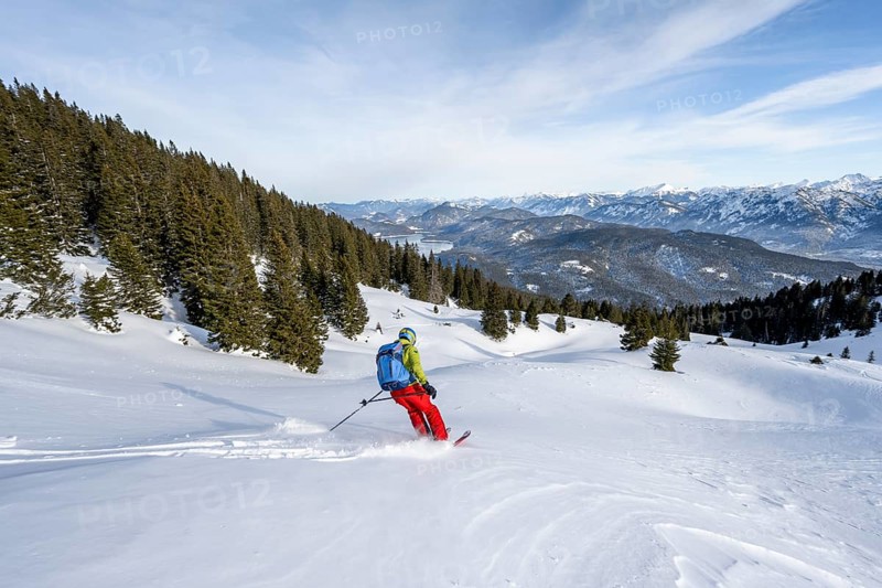 Skiers skiing down the Simetsberg, view of Walchensee and mountain panorama, Estergebirge, Bavarian Prealps, Bavaria Germany