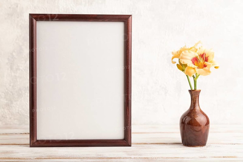 Wooden frame with orange day-lily flowers in ceramic vase on gray concrete background. side view, copy space, still life, mockup, template, spring, summer concept