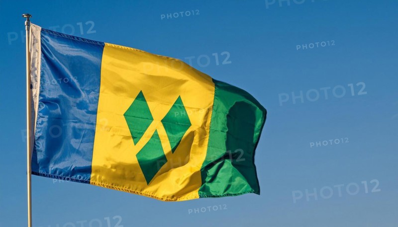 The flag of the Grenadines flutters in the wind, isolated against a blue sky