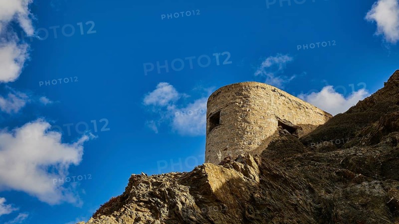 Ruin of a windmill, Stone tower on a rock, surrounded by blue sky and clouds, Colourful mountain village, Morning light, Olymbos, Karpathos, Dodecanese, Greek Islands, Greece, Europe