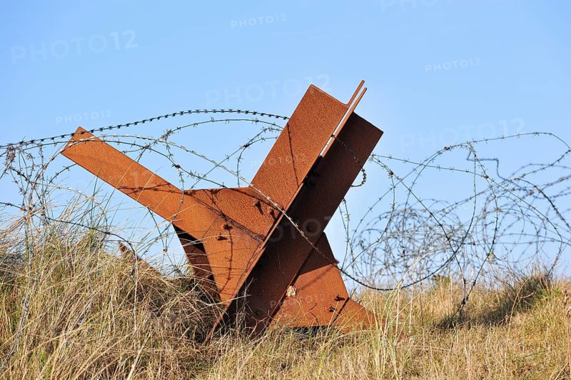 Barbed wire and Czech hedgehog static anti-tank defences from the Second World War on a beach in Normandy along the Atlantic Wall, France, Europe