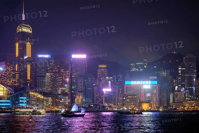 HONG KONG, CHINA, MAY 1, 2018: Hong Kong skyline cityscape downtown skyscrapers over Victoria Harbour in the evening illuminated with tourist boat and ferries. Hong Kong, China, Asia