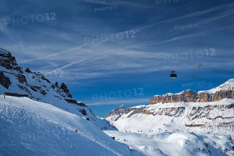 View of a ski resort piste with people skiing in Dolomites in Italy with cable car ski lift. Ski area Arabba. Arabba, Italy, Europe