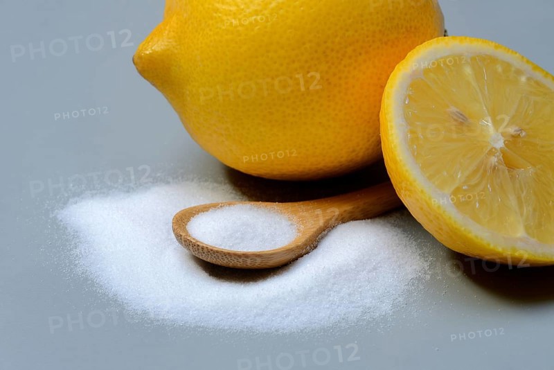 Citric acid in wooden spoon and lemon