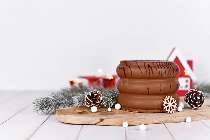 Traditional German layered winter cake showing layers inside called 'Baumkuchen' glazed with chocolate, surrounded by seasonal decoration