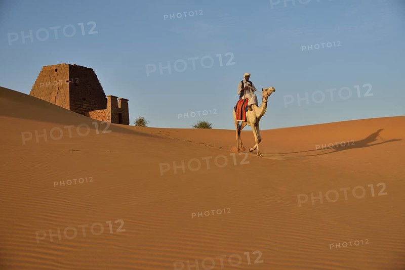 Man riding a dromedar in front of a pyramid of the northern cemetery of Meroe, Nubia, Nahr an-Nil, Sudan, Africa