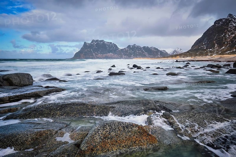 Rocks on beach of fjord of Norwegian sea in winter with snow. Utakliev beach, Lofoten islands, Norway, Europe