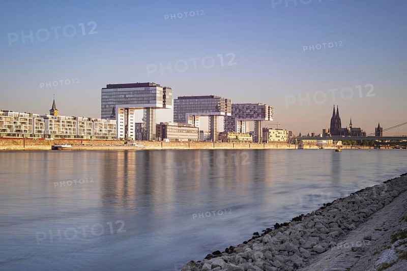 Crane houses in the Rheinau harbour and Cologne Cathedral seen across the Rhine from the bollard meadows in Cologne-Deutz, Cologne, North Rhine-Westphalia, Germany, Europe