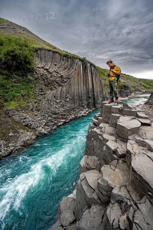 Tourist standing by the river in Stuðlagil Canyon, turquoise blue river between basalt columns, Egilsstadir, Iceland, Europe