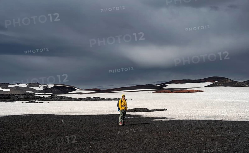 Hikers in snow-covered volcanic landscape with volcanic sand and petrified lava, crater of Askja volcano, Icelandic highlands, Iceland, Europe