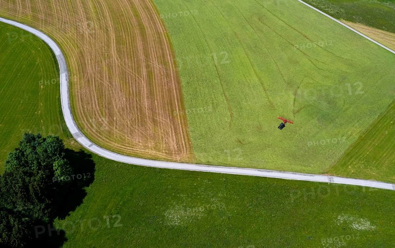 Drone view of a tractor turning hay in the field, Flachgau, Land Salzurg, Austria, Europe