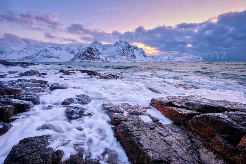 Beach of Norwegian sea on rocky coast in fjord on sunset in winter. Vareid beach, Lofoten islands, Norway, Europe