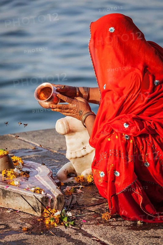 MAHESHWAR, INDIA, APRIL 26: Indian woman performs morning pooja on sacred river Narmada ghats on April 26, 2011 in Maheshwar, Madhya Pradesh, India. To Hindus Narmada is one of 5 holy rivers of India