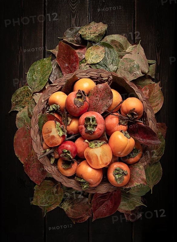 Fresh persimmon in a basket, with leaves, top view, no people