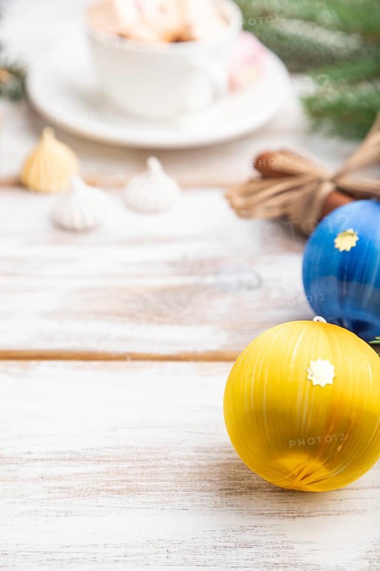 Christmas or New Year frame composition. Decorations, box, balls, cinnamon, ribbons, fir and spruce branches, cup of coffee, on a white wooden background. Side view, copy space, selective focus