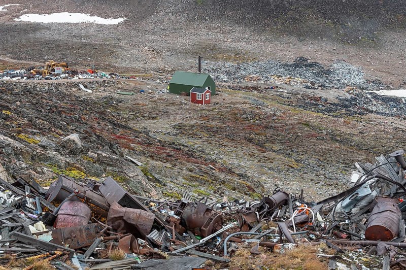 Cabin near scrap yard in rocky, hilly landscape with snow remains, arctic settlement Ittoqqortoormiit, Scoresbysund or Scoresby Sund or Greenlandic Kangertittivaq, East Greenland, Greenland, North America