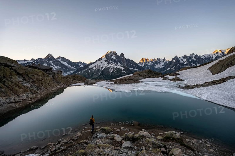 Tourist at a mountain lake in the morning, mountain landscape at sunrise, Lac Blanc, mountain peak, Aiguille Verte, Grandes Jorasses, Aiguille du Moine, Mont Blanc, Mont Blanc massif, Chamonix-Mont-Blanc, Haute-Savoie, France, Europe