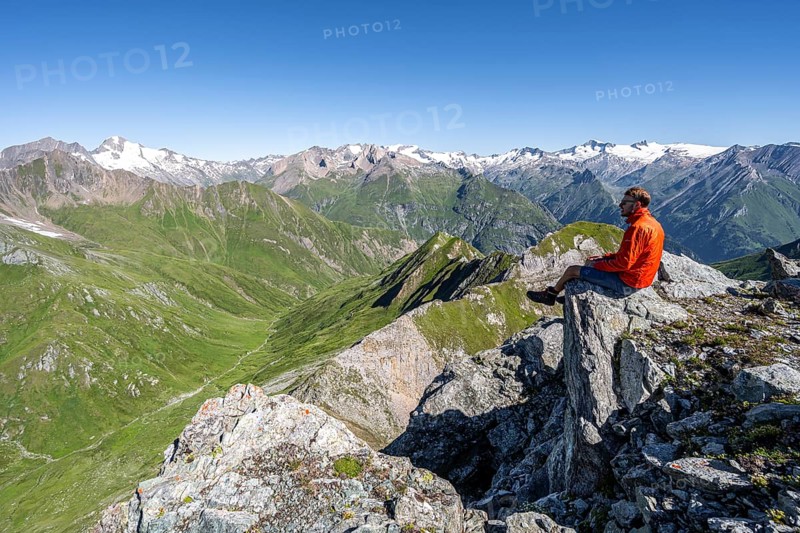 Mountaineer sitting on a rock in front of a mountain panorama with Großvenediger, mountain landscape with mountain peaks of the Venediger group, view from the summit of the Gösleswand, Lasörling group, Hohe Tauern National Park, East Tyrol, Tyrol, Austria, Europe