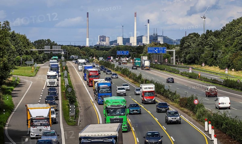 Bottrop, Ruhr area, North Rhine-Westphalia, Germany, rush hour traffic, many lorries driving on the A2 motorway, behind the Uniper coal-fired power plant Gelsenkirchen Scholven, on the right a wind turbine, industry and traffic in the Ruhr area, Europe