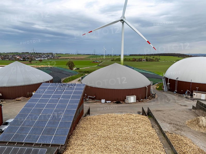 Biogas plant produces gas from various biomass, here the sugar beet store, the electricity is produced in combined heat and power plants with the biogas produced and sold to companies in the neighbouring industrial estate, the heat generated is fed into a local heating network, gas storage technical building with solar roofs and wind power plant, Ense, North Rhine-Westphalia, Germany, Europe