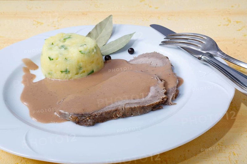 German cuisine, Sauerbraten with mashed potatoes, rocket mashed potatoes, meat dish, beef, braised meat, main course, served on a plate, gravy, dried bay leaves, juniper berries, grandmother's cooking, regional, silver cutlery, home cooking, traditional cuisine reinterpreted, food photography, studio, Germany, Europe