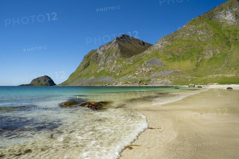 Landscape with sea at the sandy beach of Haukland with the mountain Veggen. Shot during the day with blue sky. Early summer. Haukland Beach, Haukland, Vestvagoya, Lofoten, Norway, Europe