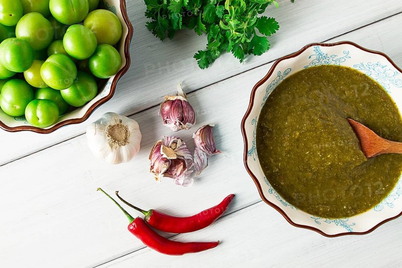 Tkemali sauce, traditional Georgian cuisine, green cherry plum, with ingredients for sauce, cilantro, mint, hot pepper, garlic, on a white wooden table, close-up, rustic, food background, no people, selective focus, sauce, green sauce, tkemali, georgian cuisine, homemade