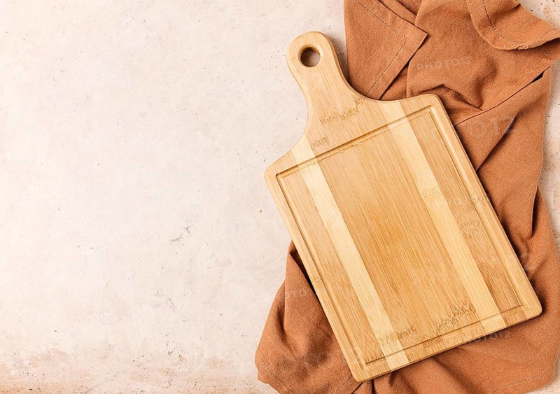 Cutting board, beige, unpainted, with a kitchen towel, on a beige background, top view