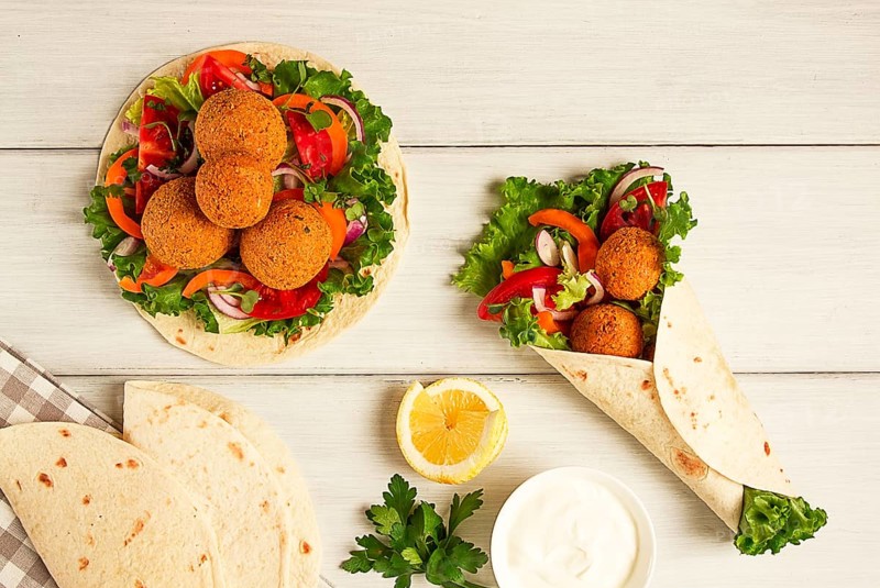 Tortillas, wrapped falafel balls, with fresh vegetables, vegetarian healthy food, on a wooden white background, no people, selective focus