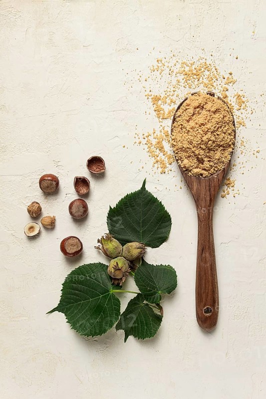 Wooden spoon with hazelnut flour, top view, no people, on a white table