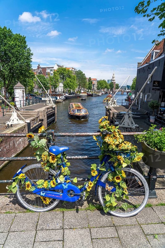 Sint Antoniesluis, on the Oudeschans canal, bicycle decorated with sunflowers, canal cruise boat, café, De Sluyswacht, Amsterdam, Netherlands