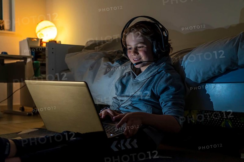 Boy, at home on the computer, laptop, in the children's room, playing a game, chatting with other children, fellow players