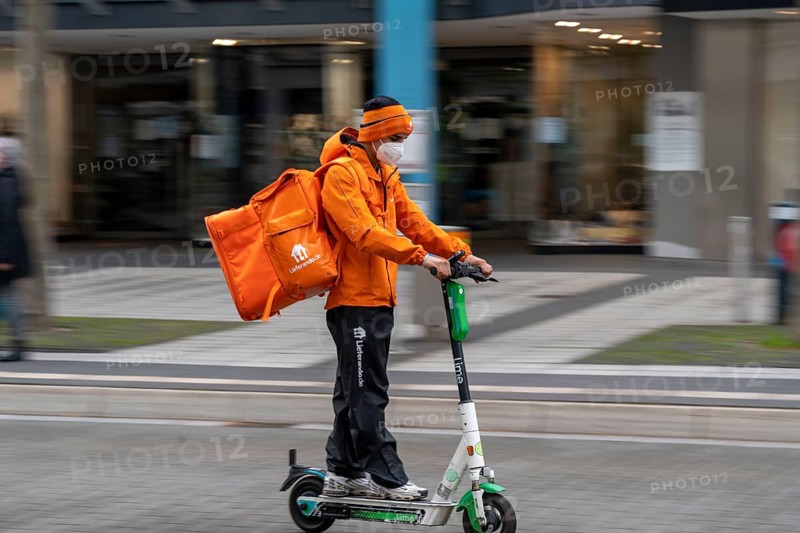 Delivery service Lieferando.de, delivery courier with e-scooter in the city centre, Rathenaustraße, in Bochum, North Rhine-Westphalia Germany