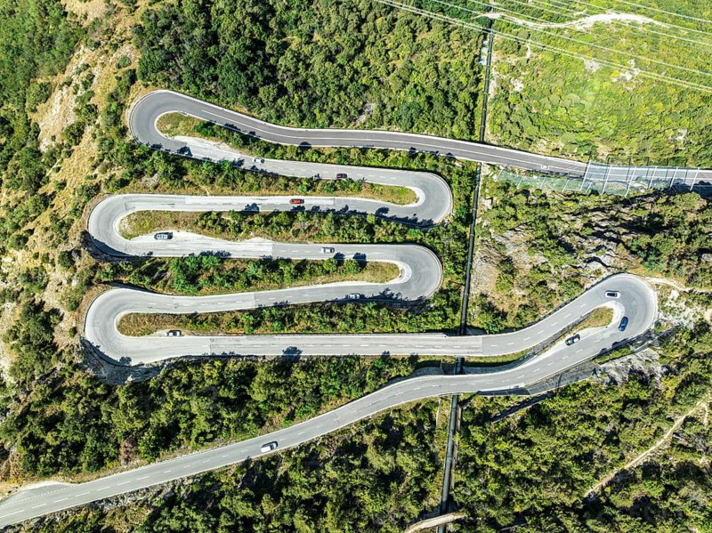 Mountain pass road with multiple hairpins, water pipeline, aerial view, drone shot. Valais, Switzerland, Europe
