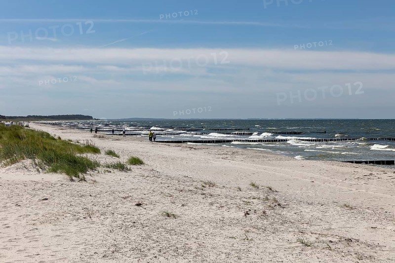 Wide beach landscape with a view of the sea and gentle waves under a blue sky, Rügen, Hiddensee