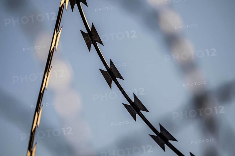 Symbolic image security, S-wire rolls, NATO wire, on a fence top, demarcation of a property, prevention of unauthorised access, strip steel wire with sharp blades